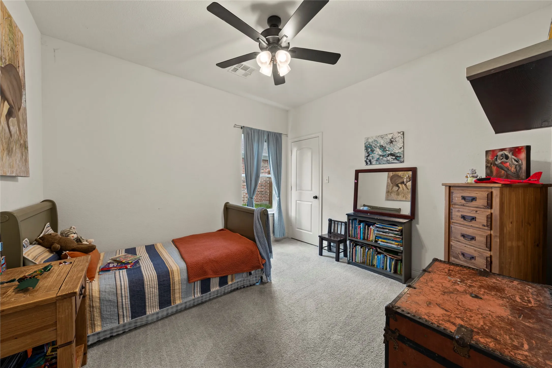 Carpeted room featuring a ceiling fan with integrated lighting, a single window with curtain rods, and a paneled interior door