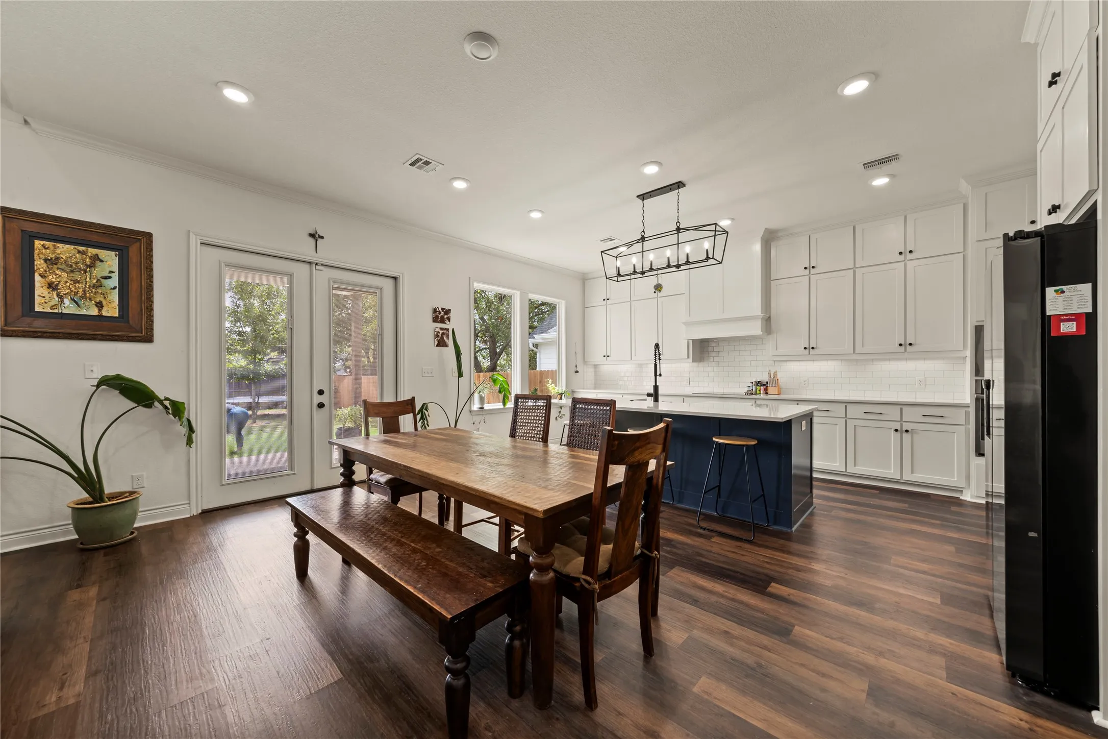 Open-concept living space featuring wood-finish flooring, recessed lighting, and a kitchen with white cabinetry and a contrasting island
