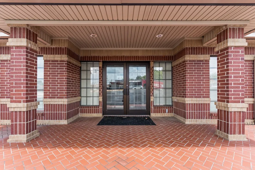 Brick exterior with stone accents, recessed lighting, and a red brick herringbone pattern entryway