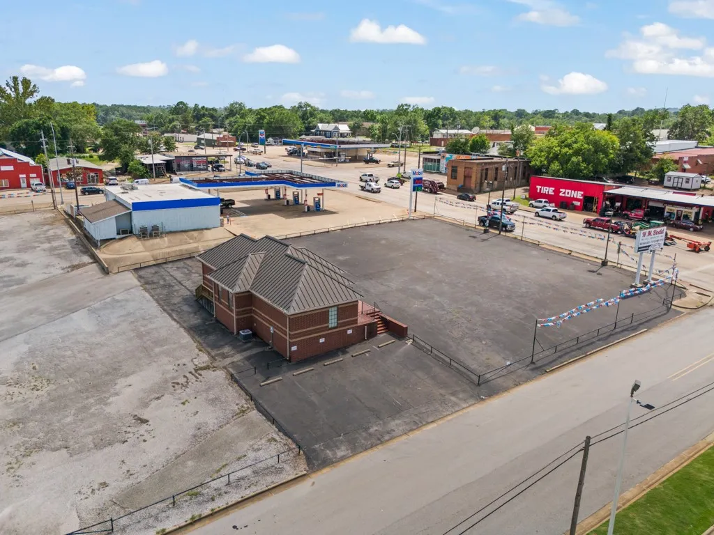 Brick exterior building with a multi-gabled roof, extensive paved lot, and street frontage