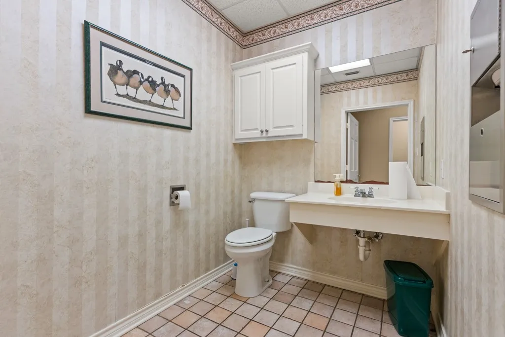 Wall-mounted sink with metal fixtures, white cabinetry, and tiled flooring