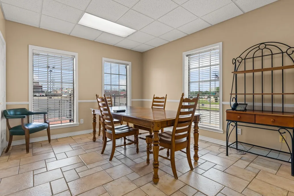 Neutral-toned wall paint, decorative chair rail molding, two windows with blinds, drop ceiling with recessed lighting, and tile flooring