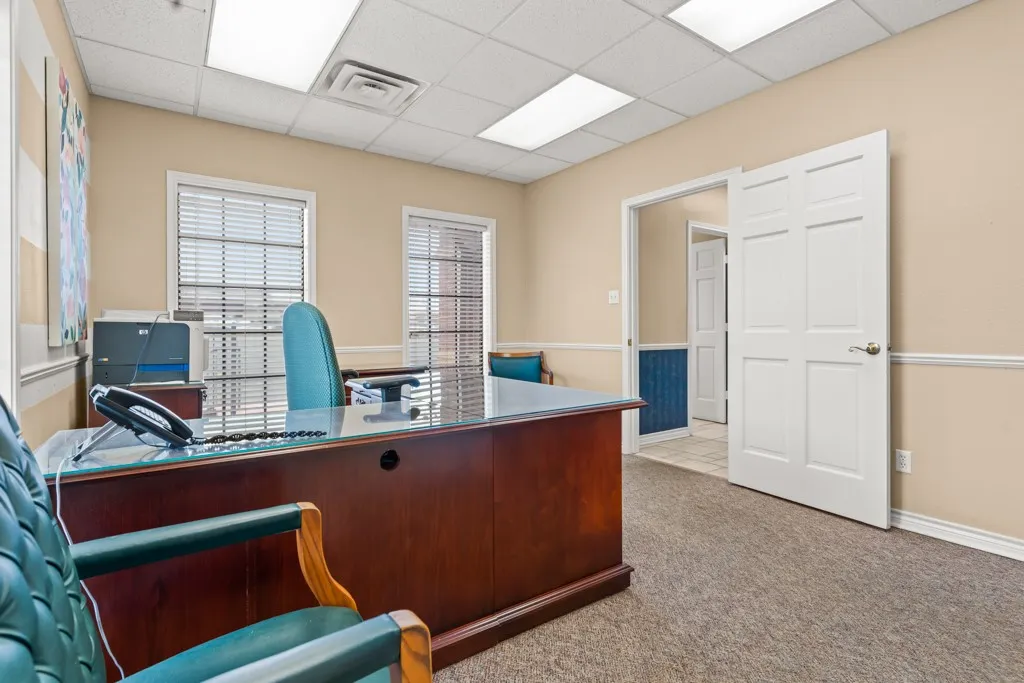 Neutral-toned walls with wainscoting, textured carpet flooring, and two windows with blinds