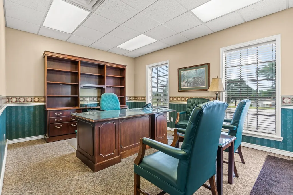 Built-in shelving unit, dual windows with blinds, drop ceiling with integrated lighting, and wall paneling
