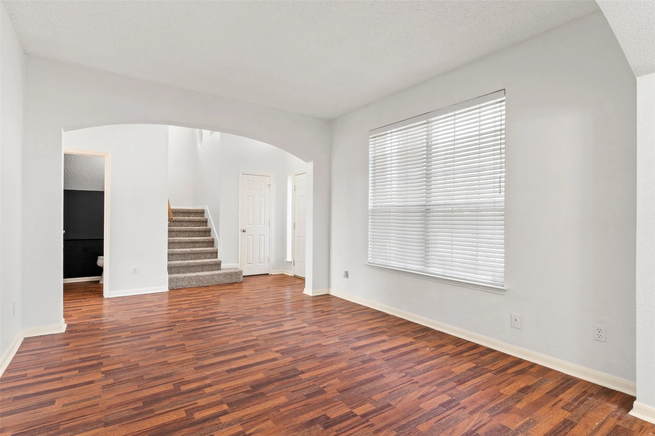 Vacant front living room overlooking entry and stairs.