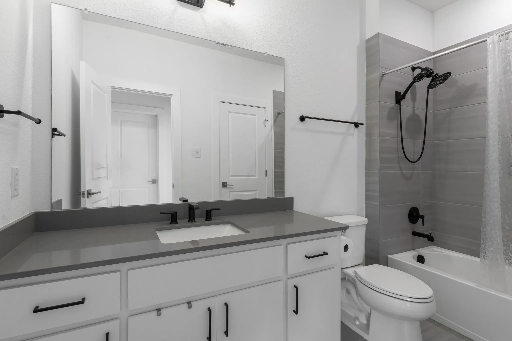 White vanity with matte black hardware, gray countertop, undermount sink, and black fixtures