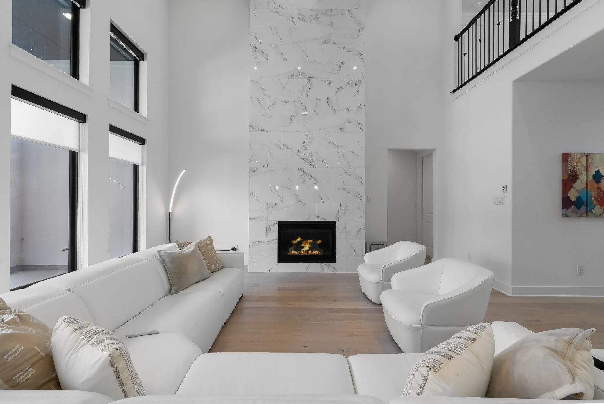 Two-story living area with high ceilings, a grand fireplace featuring a floor-to-ceiling stone-look surround, and wood-finish flooring