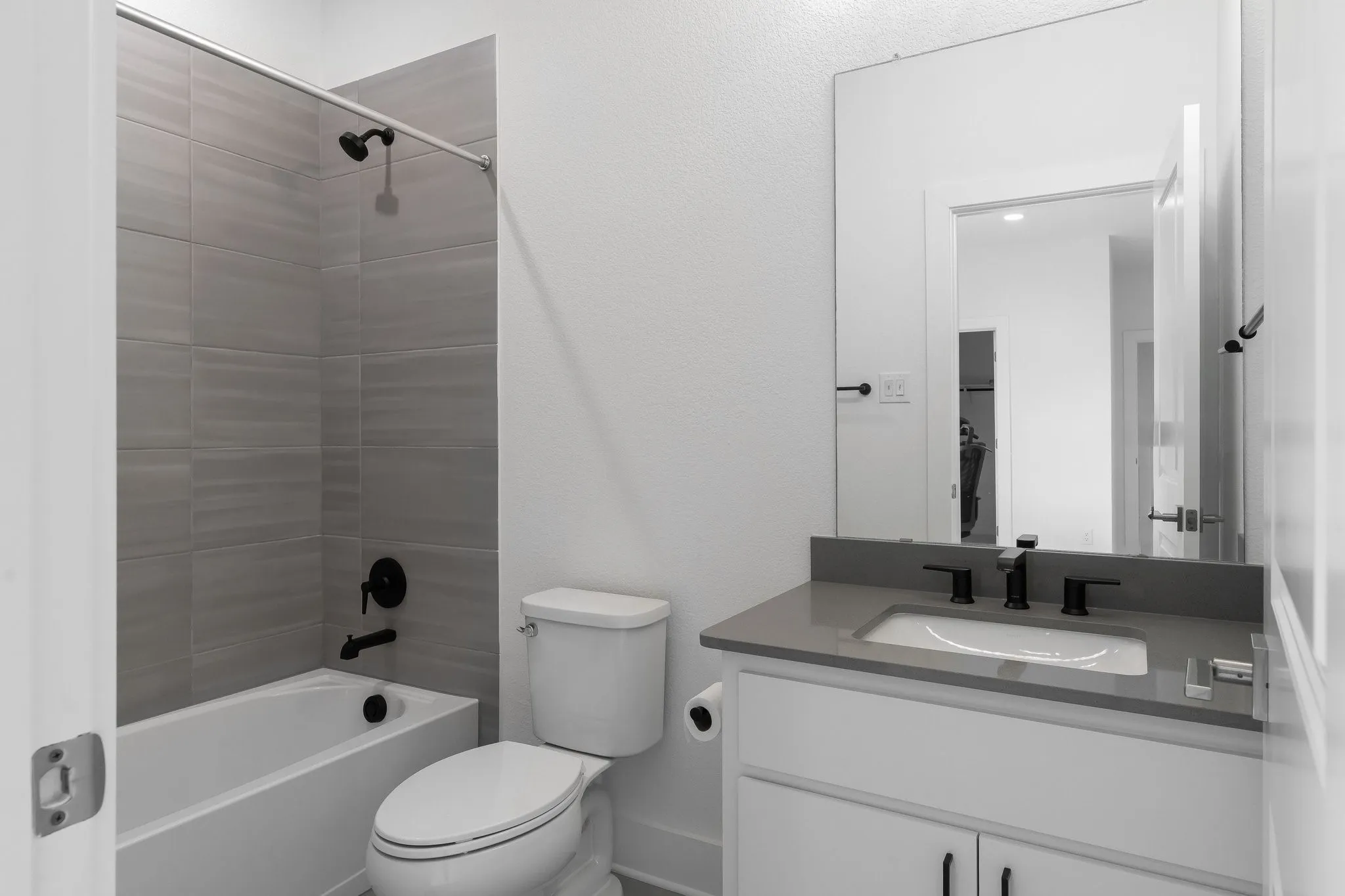 White vanity with modern black hardware, undermount sink, and light gray countertop