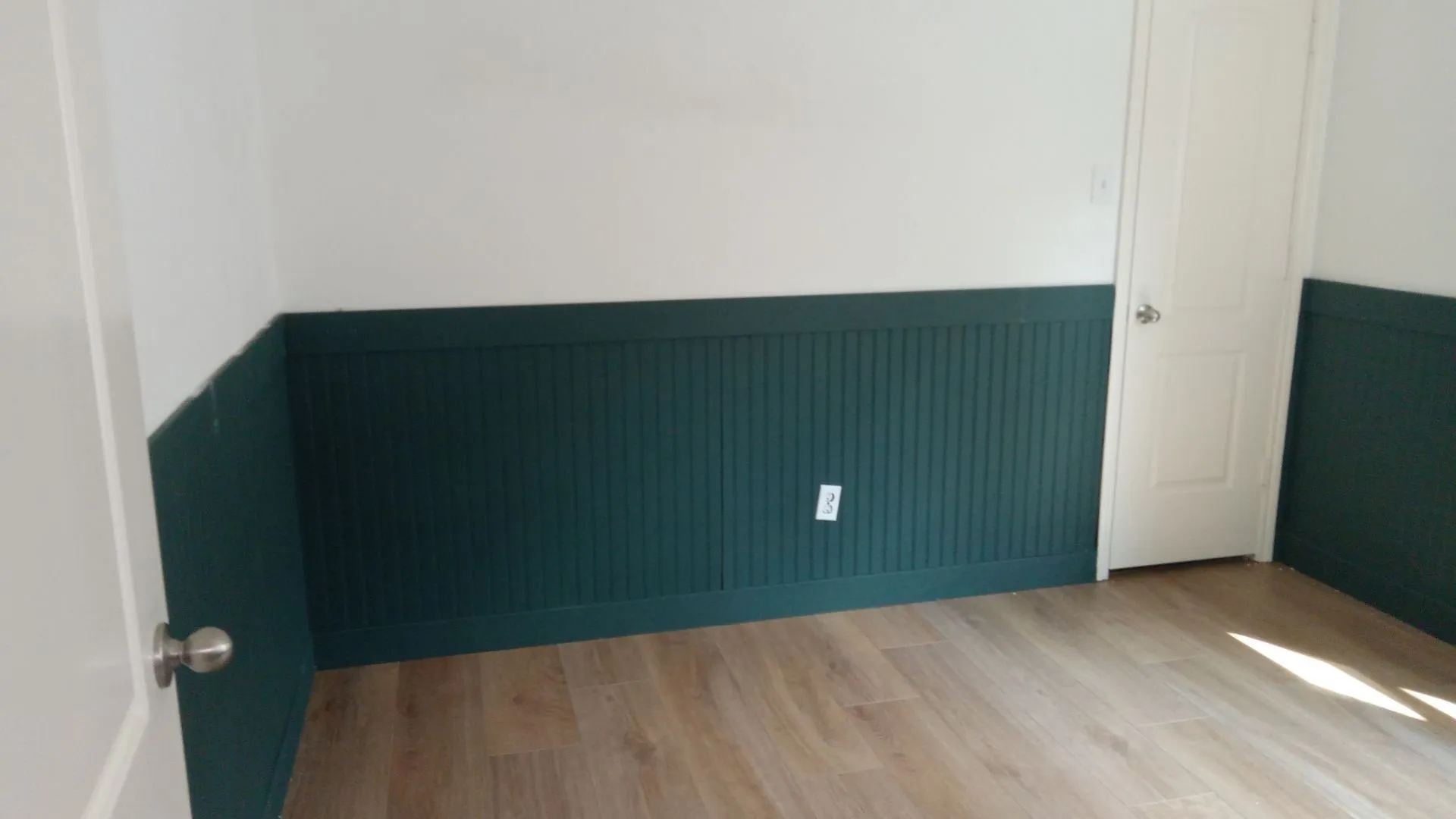 Wood-finish flooring with white walls and dark green wainscoting