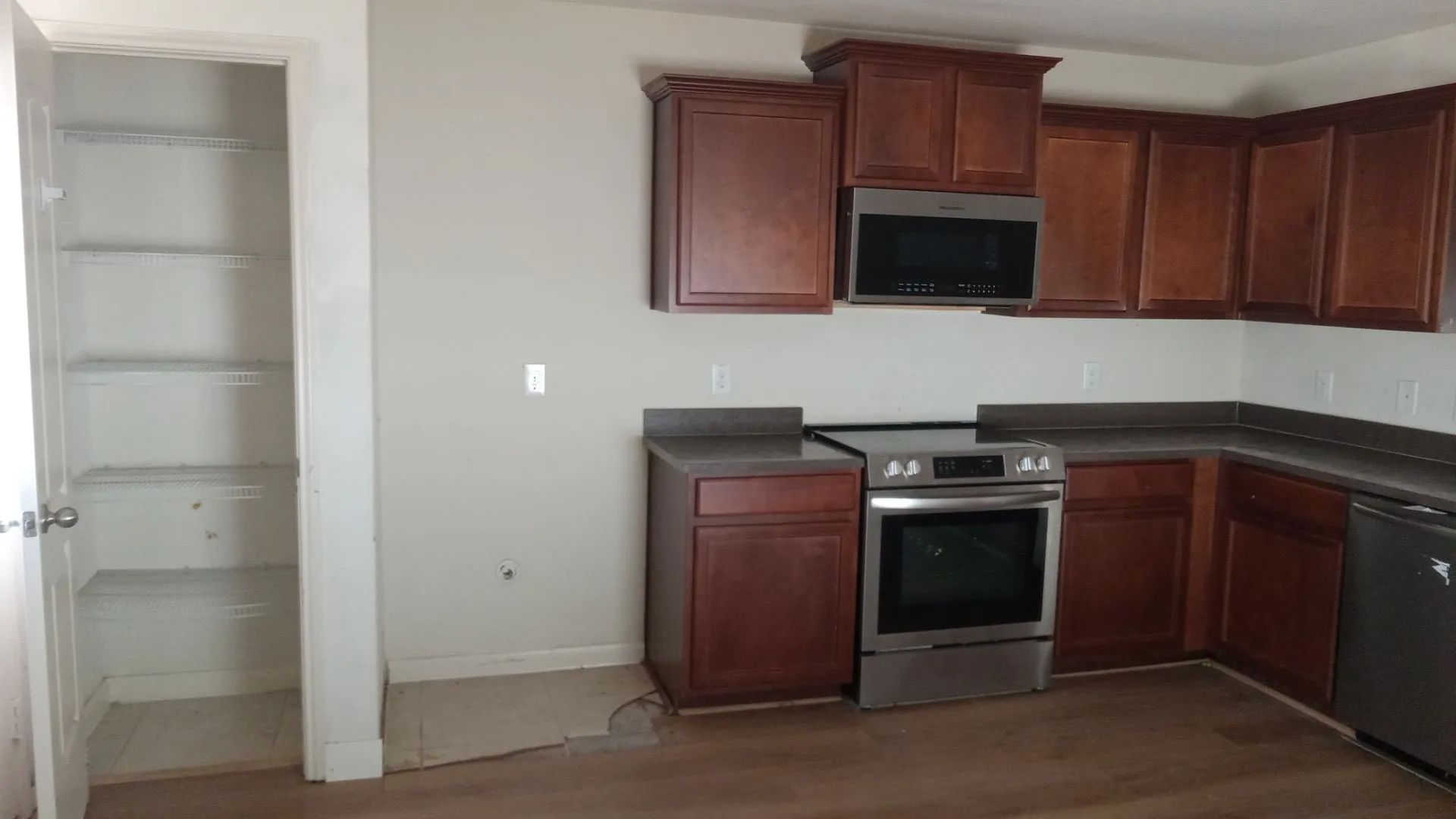 Kitchen featuring wood-finish cabinetry, solid surface countertops, a stainless steel range, and an over-the-range microwave