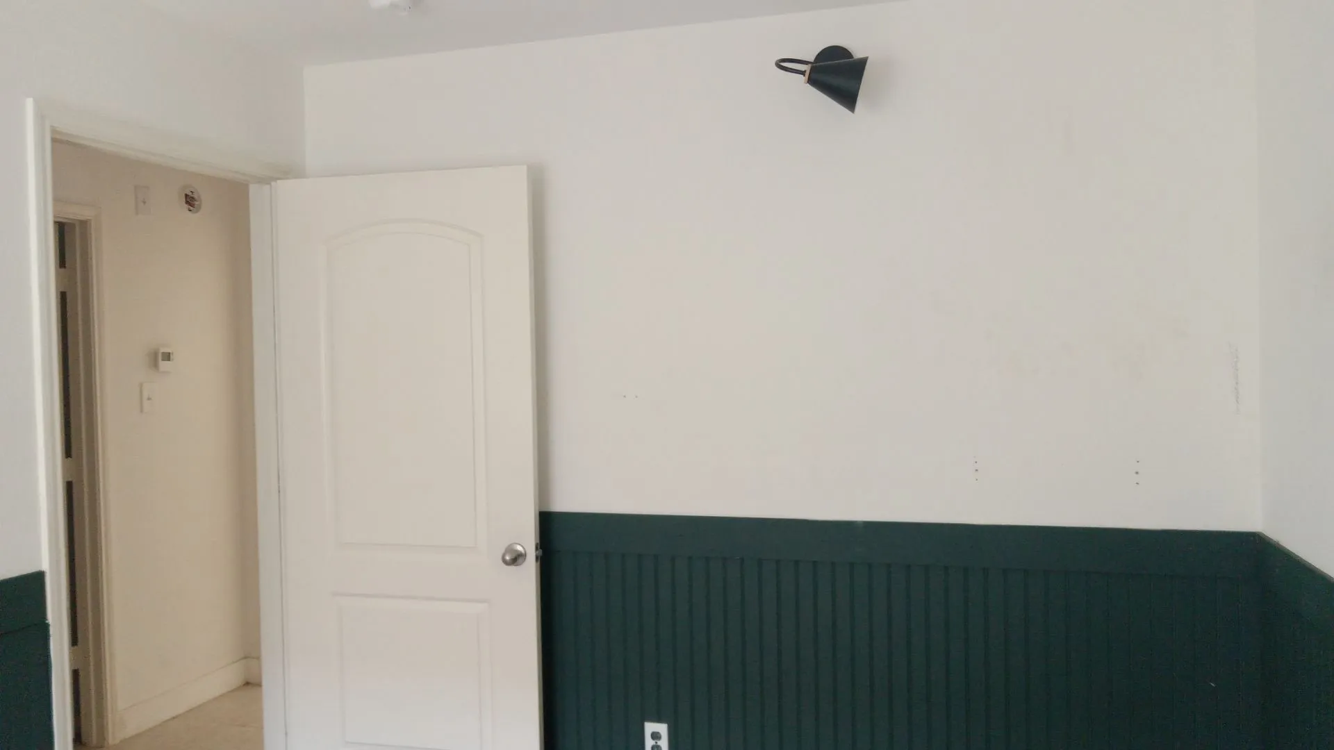 White walls with a dark green wainscoting accent, featuring a white paneled door