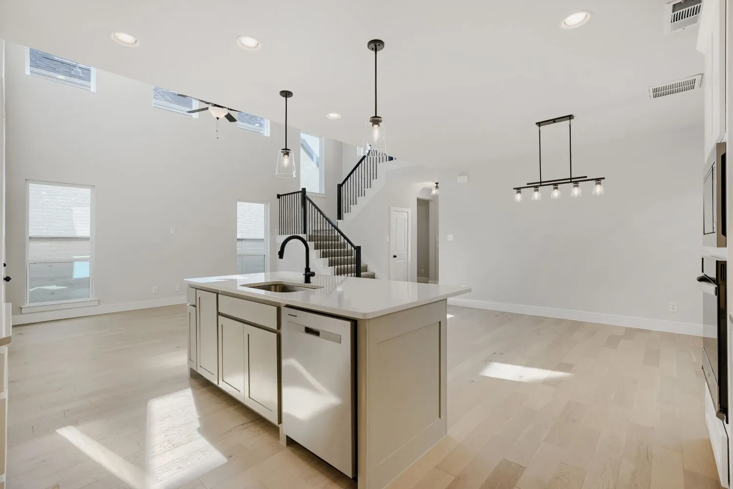 Open-concept living area with high ceilings, wood-finish flooring, and recessed lighting