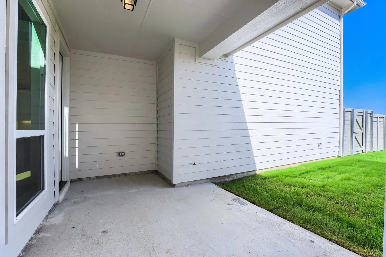 Covered patio with concrete flooring, white siding, and a privacy fence