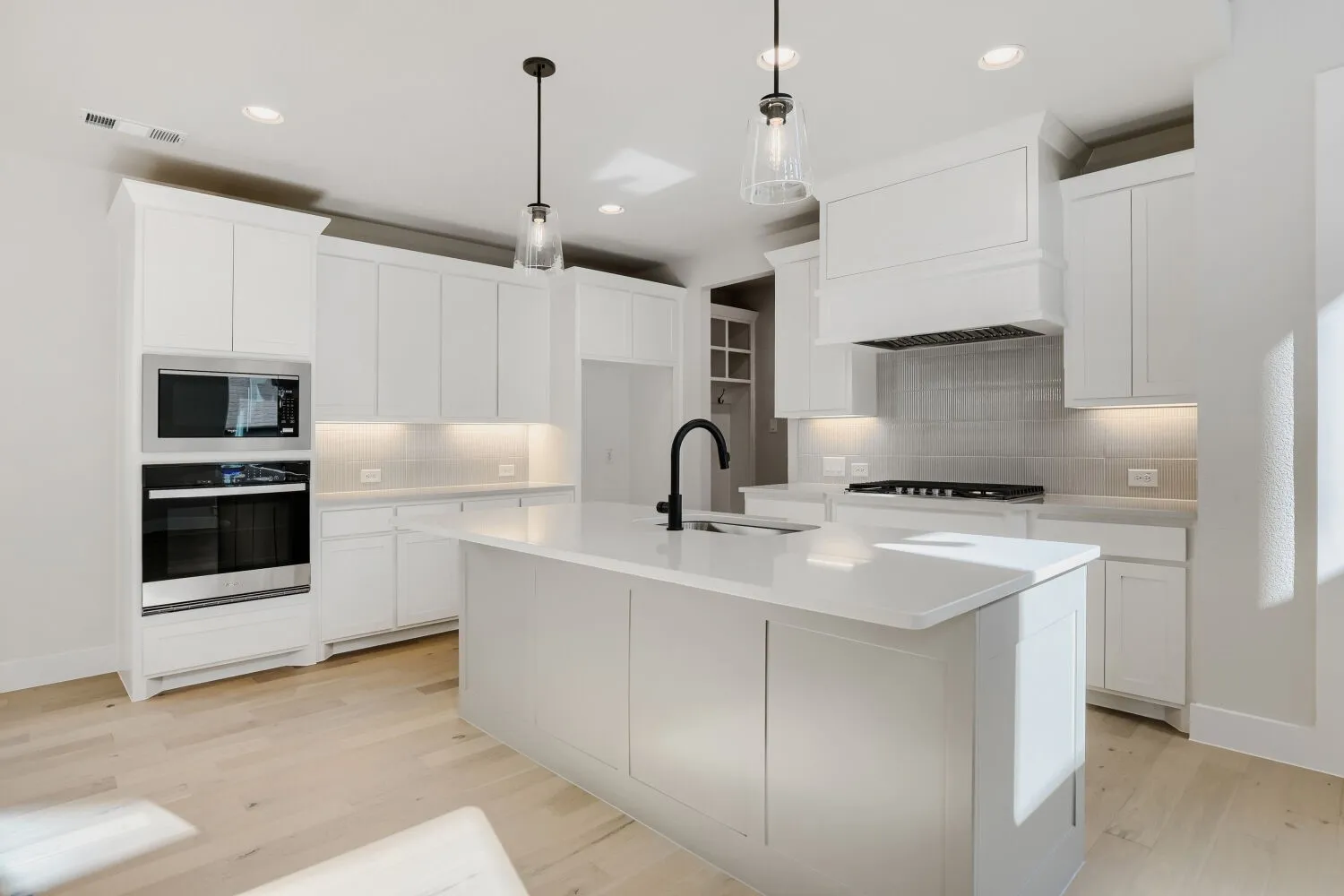 White cabinetry and a center island with a built-in sink