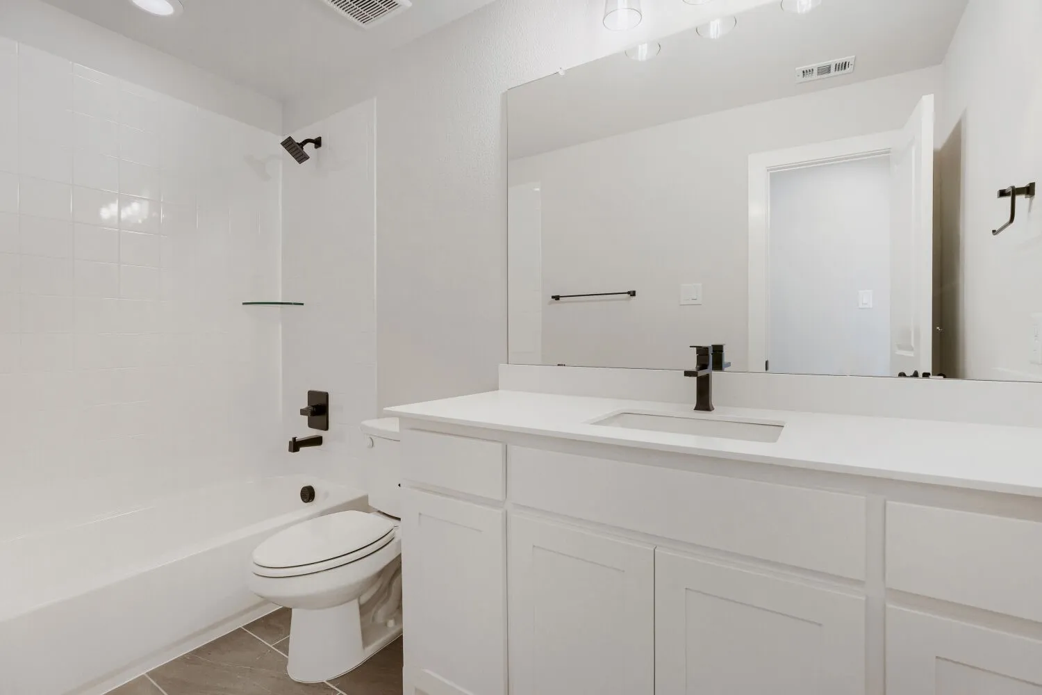 White tiled shower and tub combination featuring matte black fixtures