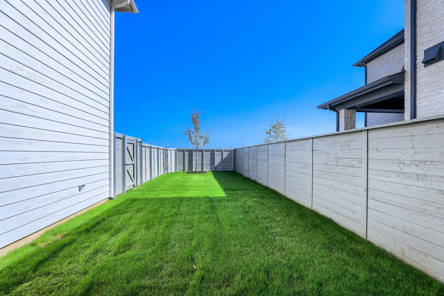 Expansive grass lawn with a full privacy fence featuring a side gate