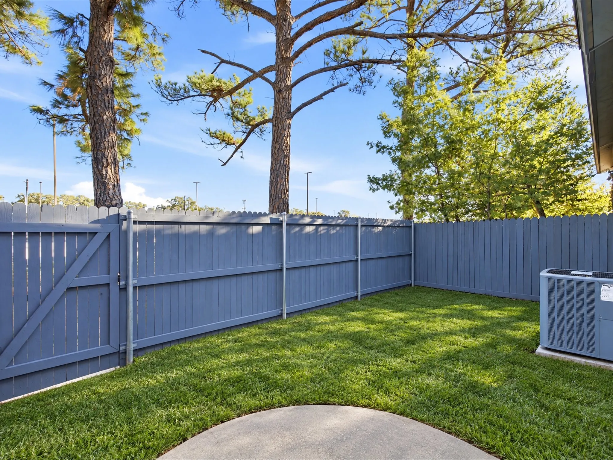 Enclosed backyard featuring a wood fence, manicured lawn, and a circular concrete patio