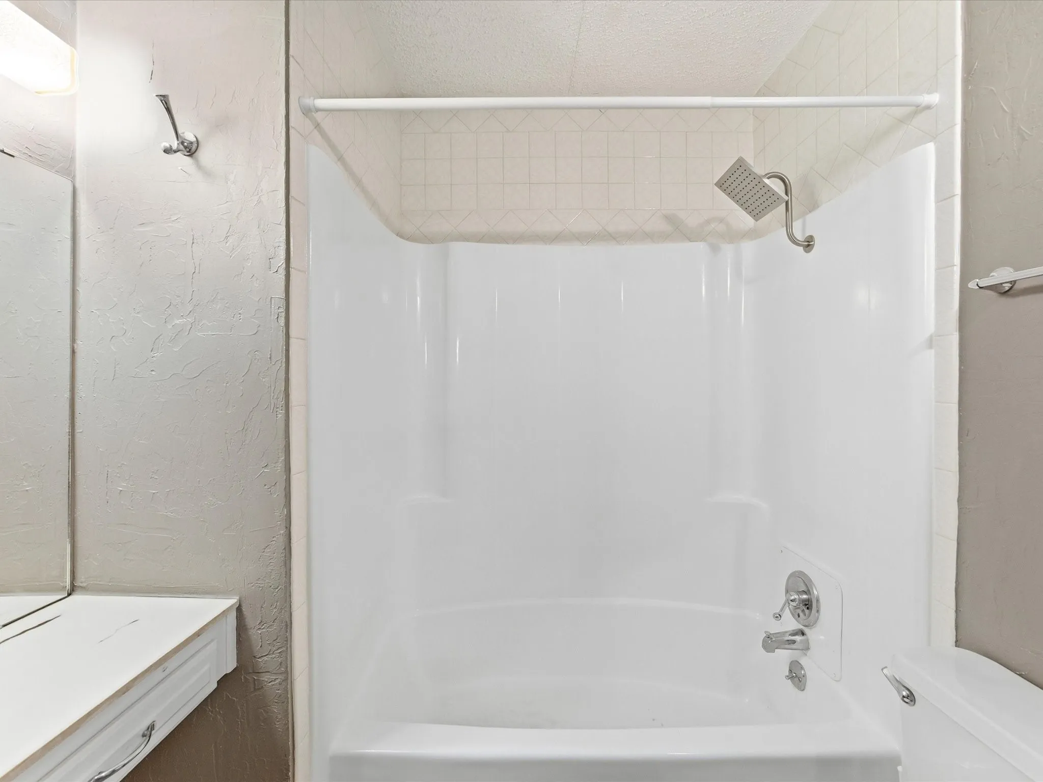 White shower-tub combination with a wall-mounted showerhead and faucet