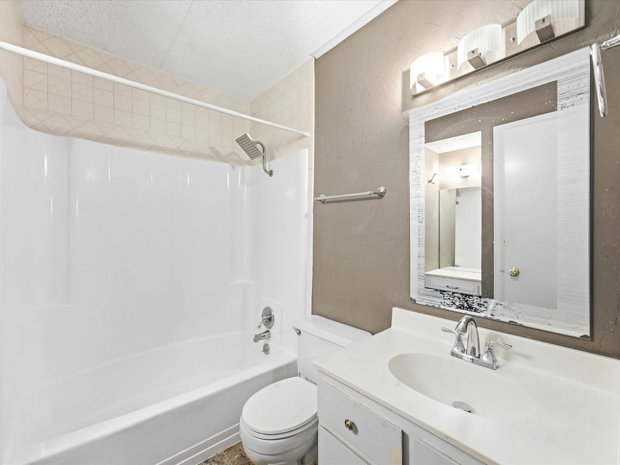 White bathtub and shower combination with a shower head, toilet, and a vanity with an integrated sink