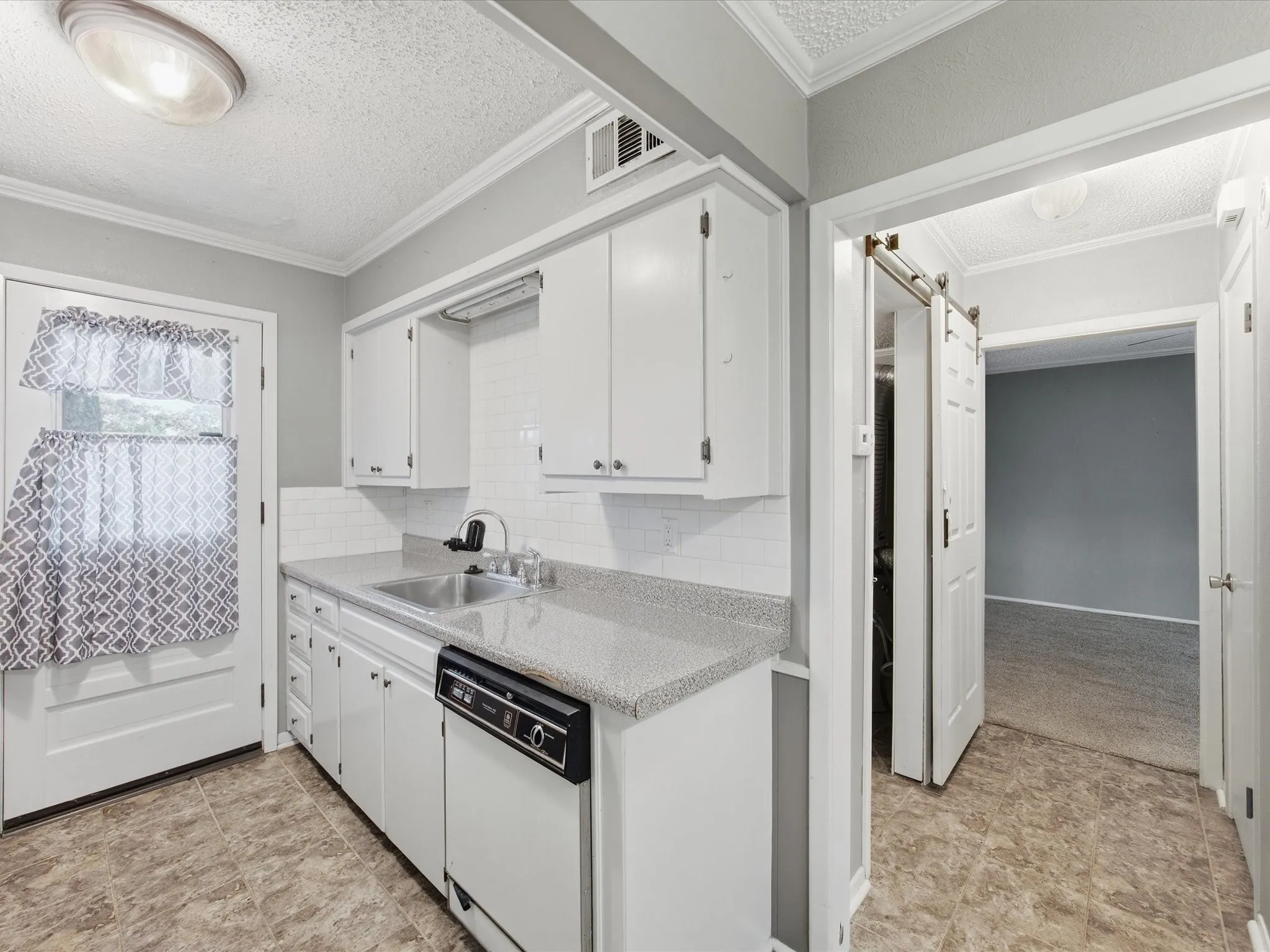 White cabinetry, subway tile backsplash, laminate countertops, and stainless steel sink