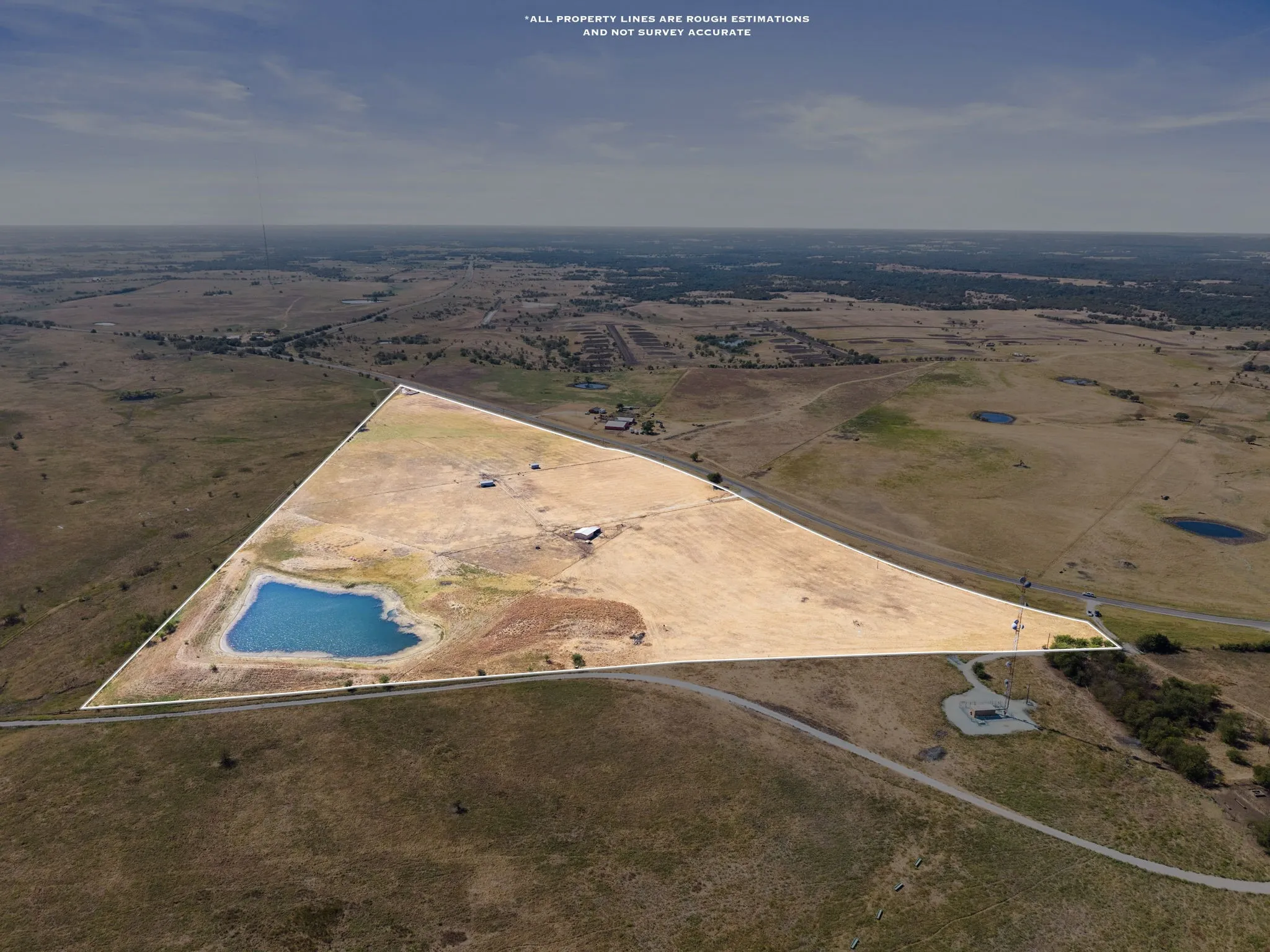 Expansive acreage featuring a private pond, open fields, and established structures
