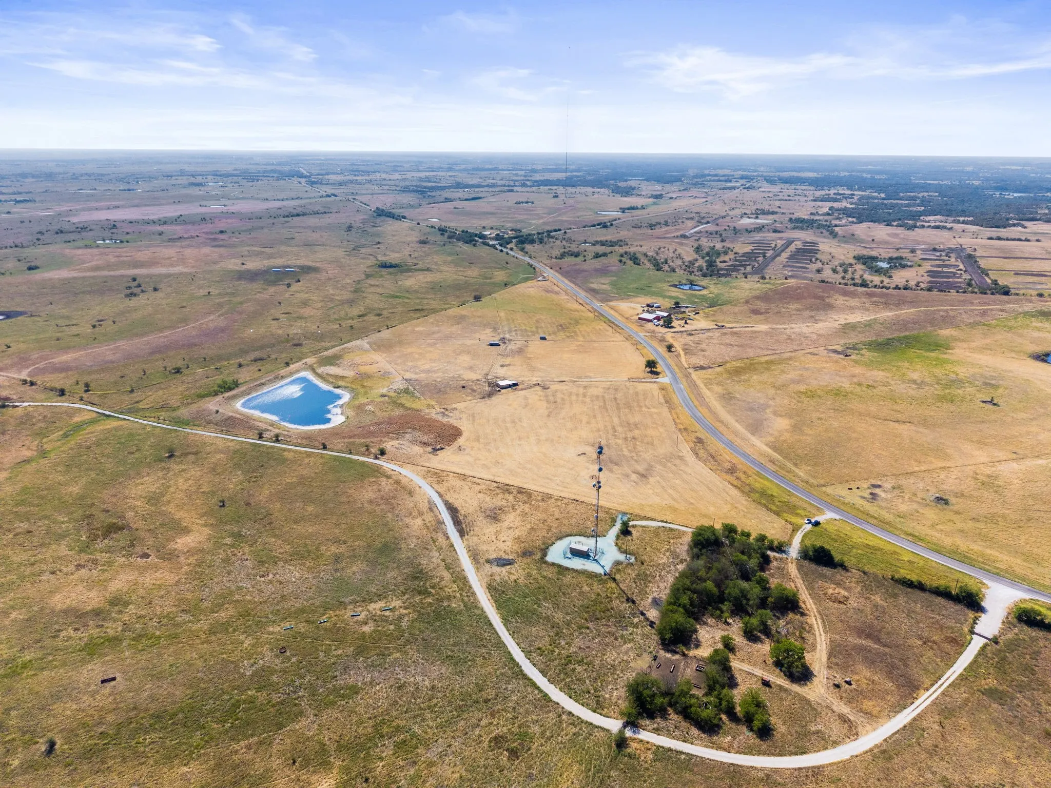 Expansive acreage featuring a natural pond, paved road frontage, and a private access drive