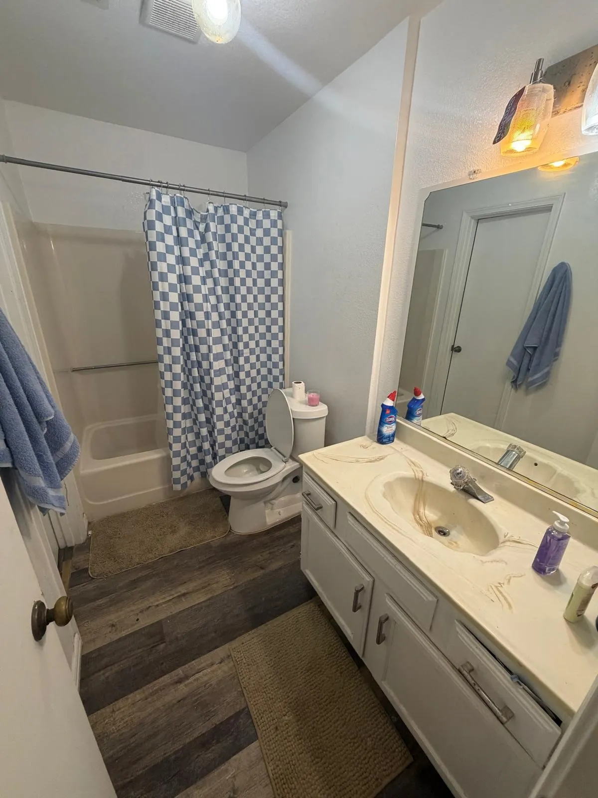 Wood-finish flooring with a white vanity featuring a built-in sink and countertop