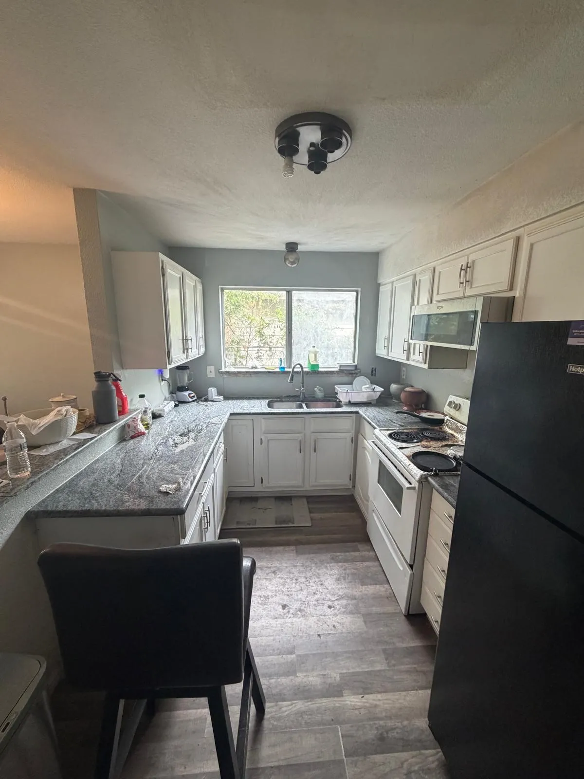 U-shaped kitchen with white cabinetry and dark stone-finish countertops