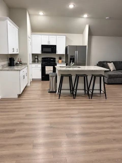 Contemporary kitchen featuring white cabinetry, light-colored granite countertops, and stainless steel appliances