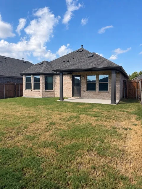 Brick exterior with a dark shingle roof and a covered patio