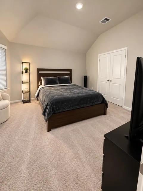 Vaulted ceiling, recessed lighting, neutral wall tones, window with blinds, and light-toned carpet