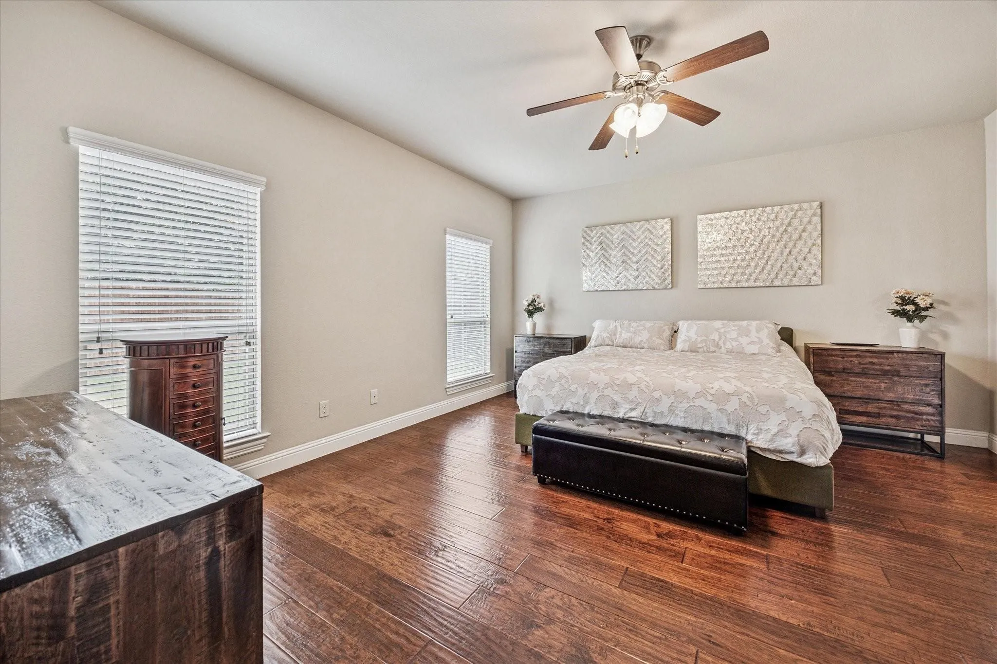 Vaulted ceiling, wood-finish flooring, two windows with blinds, and a ceiling fan with integrated lighting