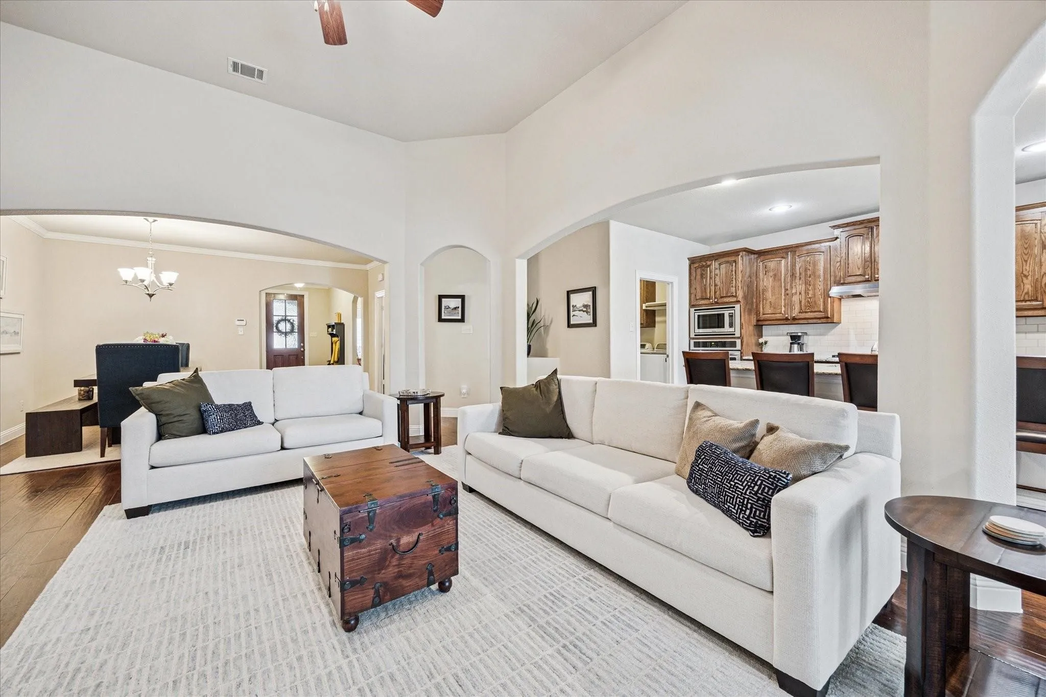 Vaulted ceiling, recessed lighting, wood-finish flooring, kitchen with built-in microwave, and arched doorways