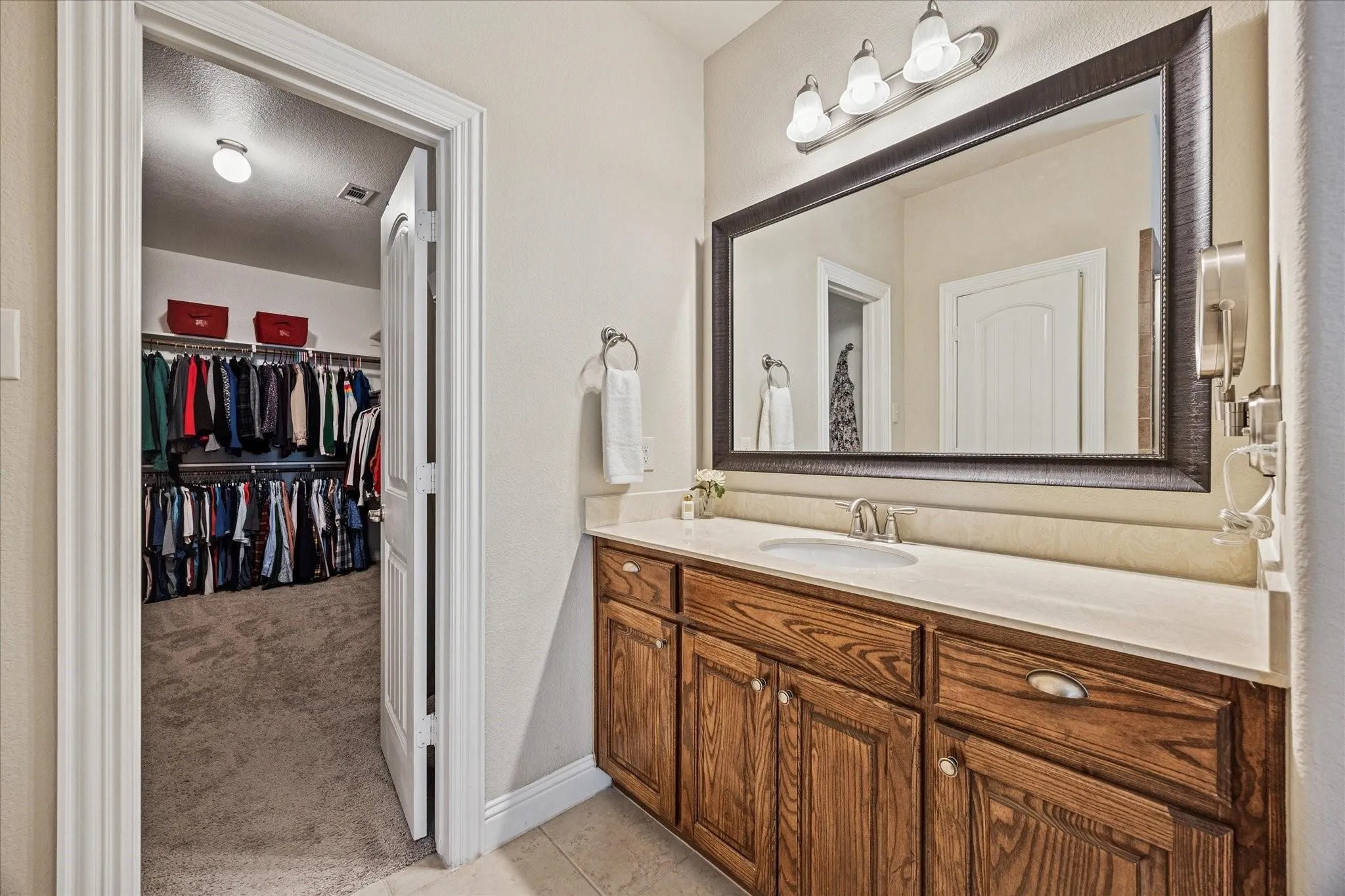 Wood-finish vanity with a single basin sink and light-toned countertop