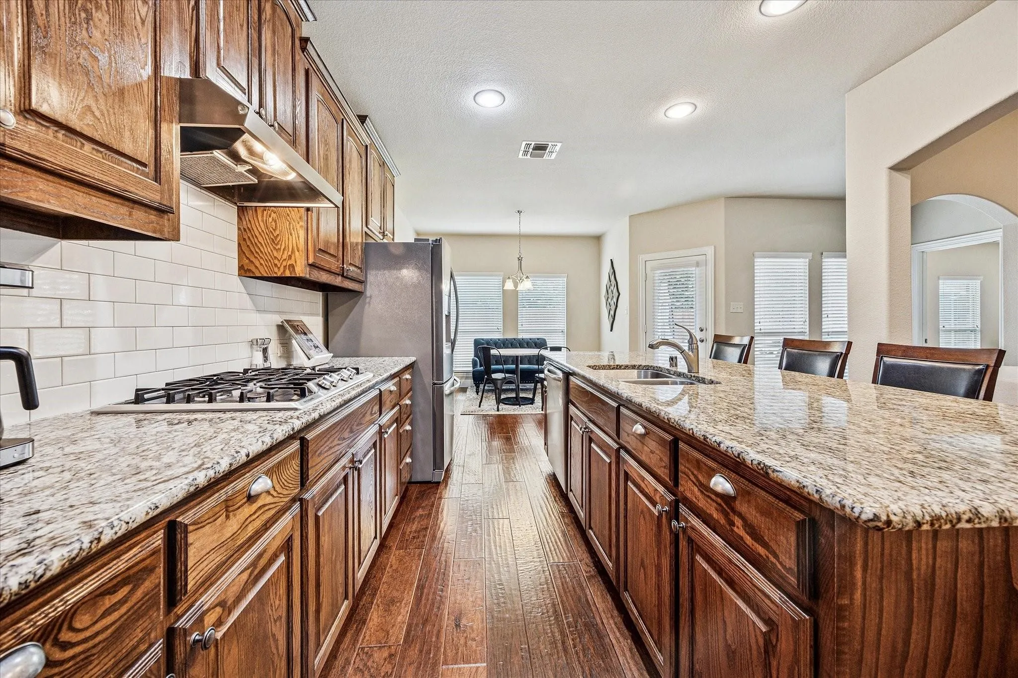 Kitchen with wood-finish flooring, recessed lighting, white subway tile backsplash, and stainless steel appliances