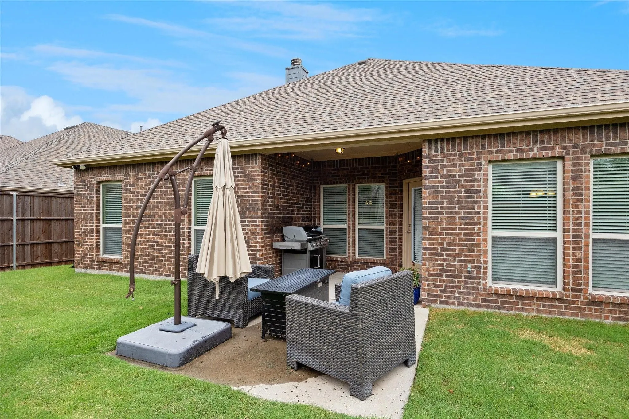 Private backyard featuring a covered patio, brick exterior, and a shingle roof