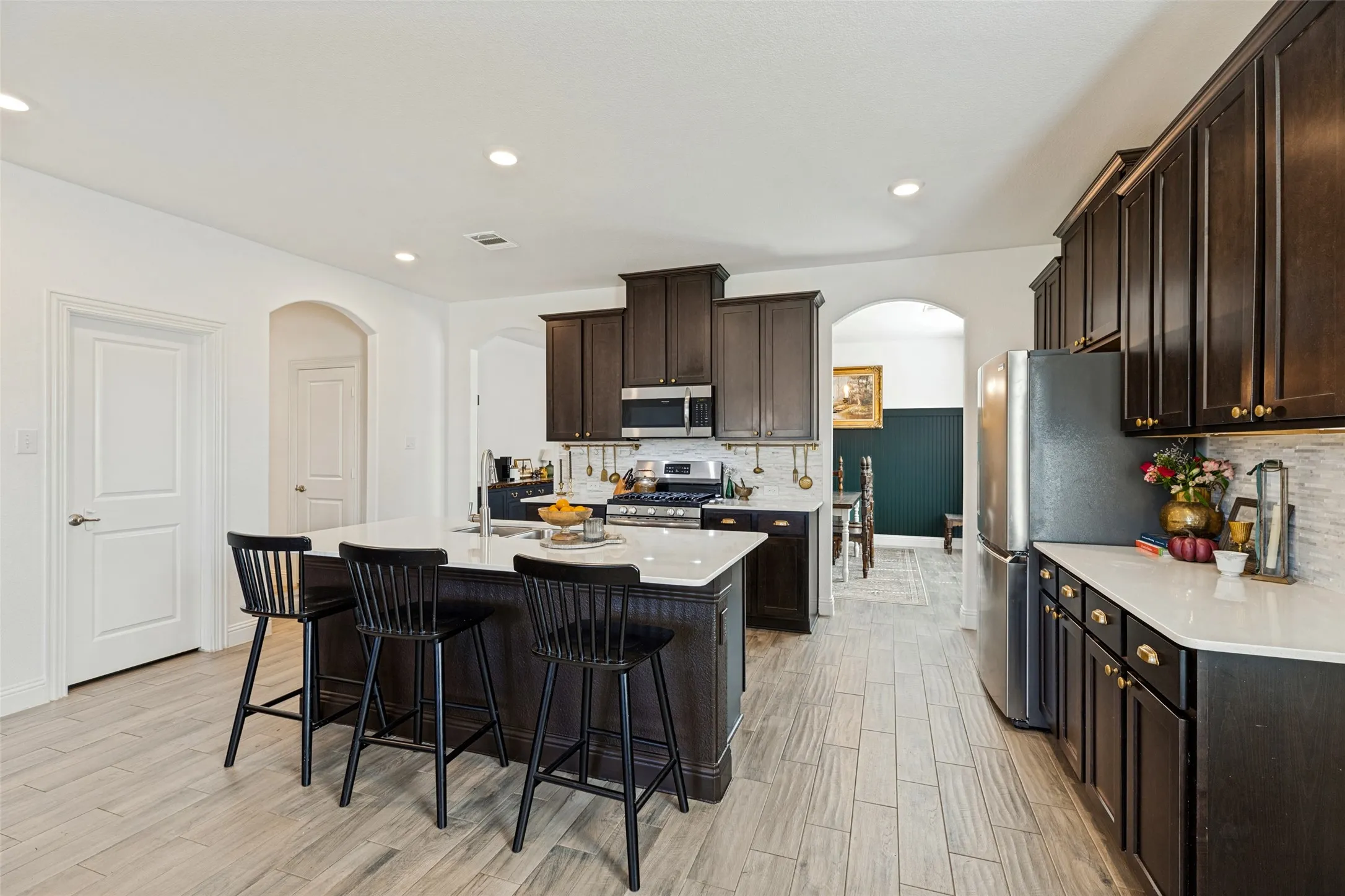 Chef's kitchen showcasing dark wood cabinetry, stainless steel appliances, white quartz countertops, and a large center island with seating