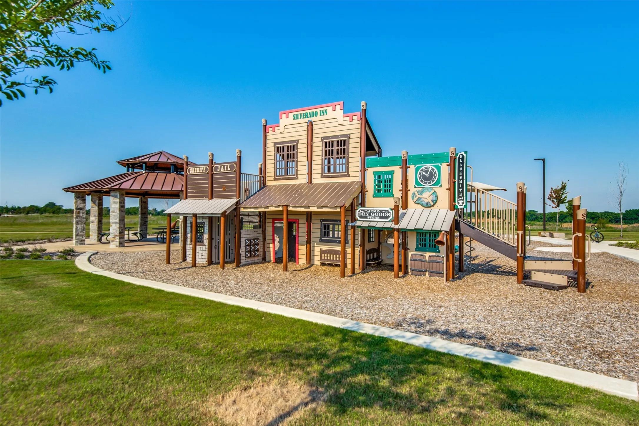 Playground structure with multiple levels and slides, featuring a western town facade