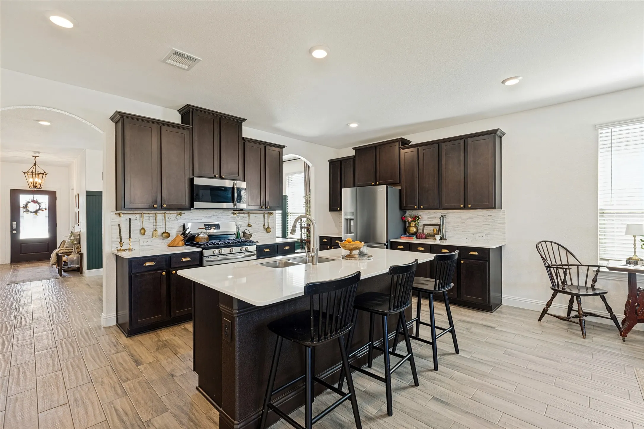 Kitchen featuring dark wood cabinetry, white stone countertops, and stainless steel appliances