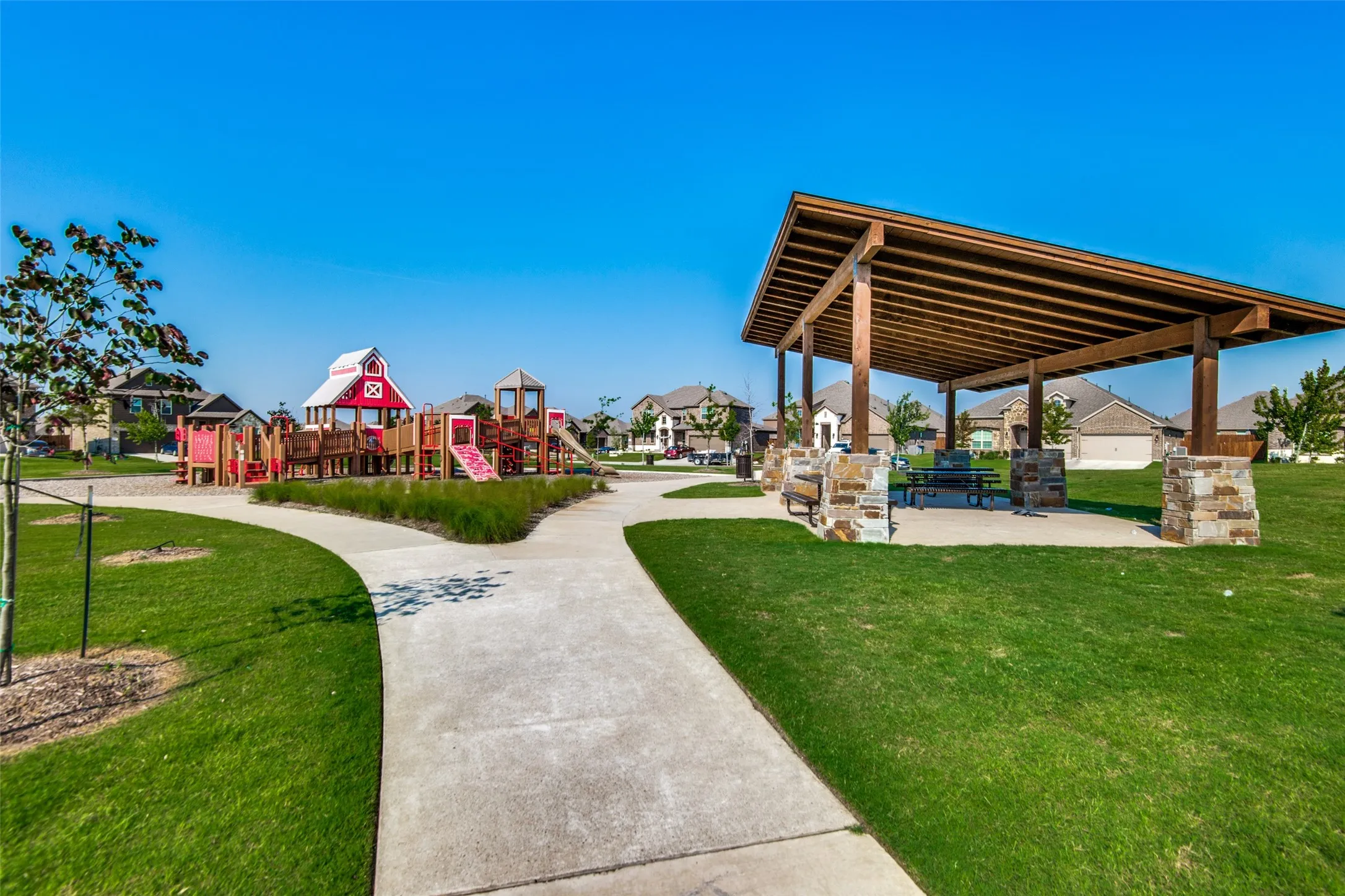 Community park with a playground structure, covered picnic area, and paved walking paths