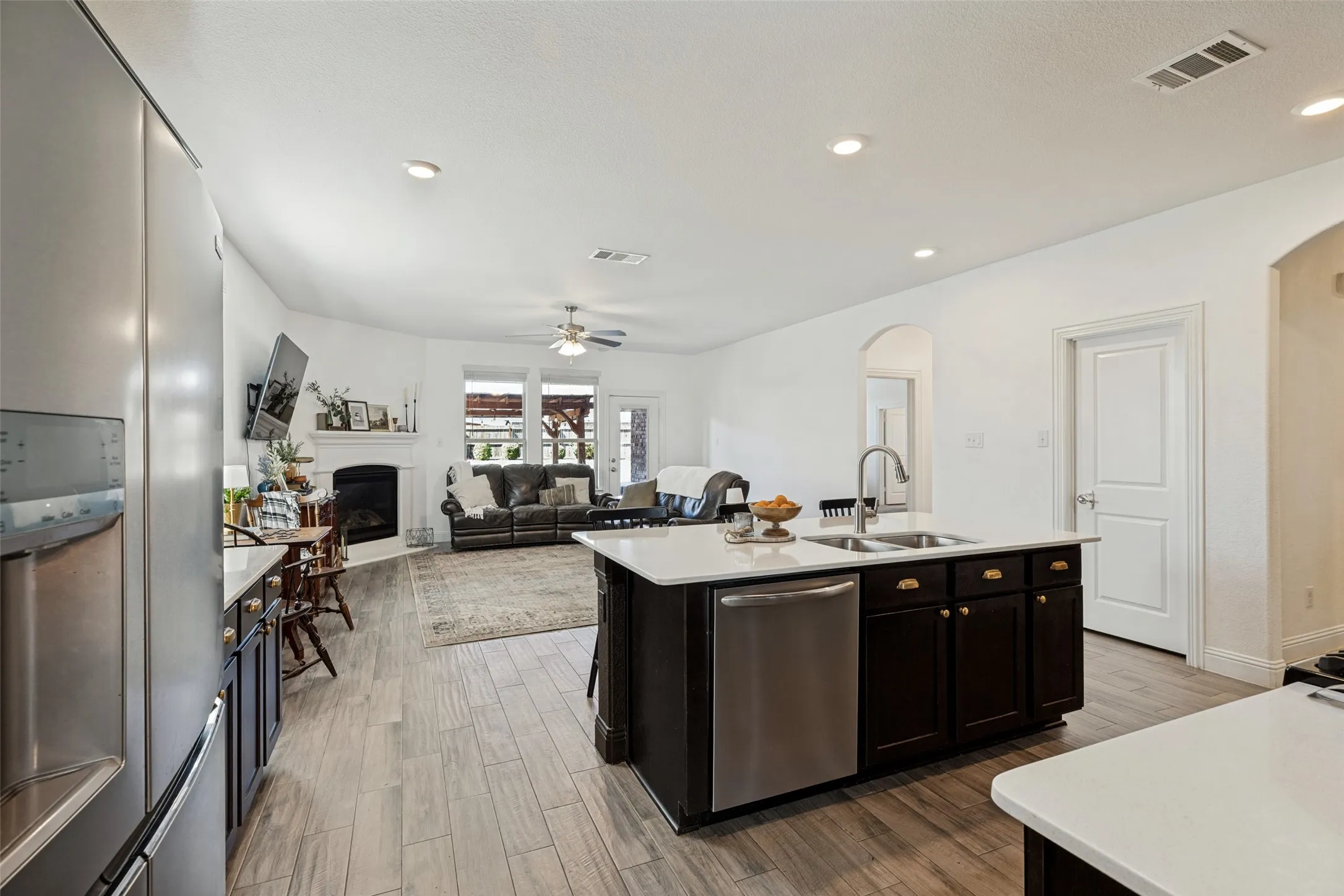 Open-concept living space featuring wood-finish flooring, recessed lighting, and a kitchen island with a stainless steel sink and dishwasher