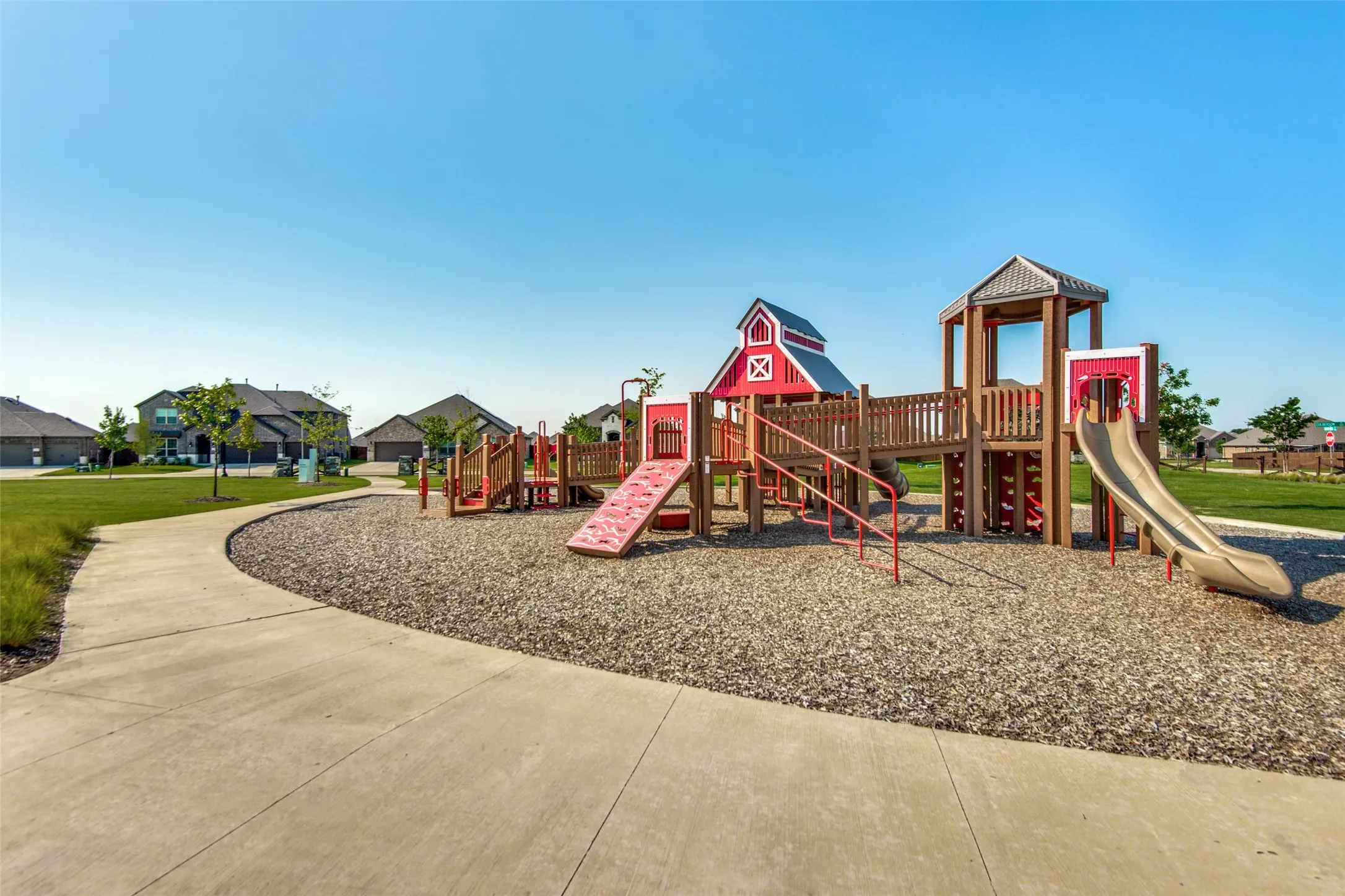 Community playground featuring multiple slides, climbing elements, and a barn-style play structure
