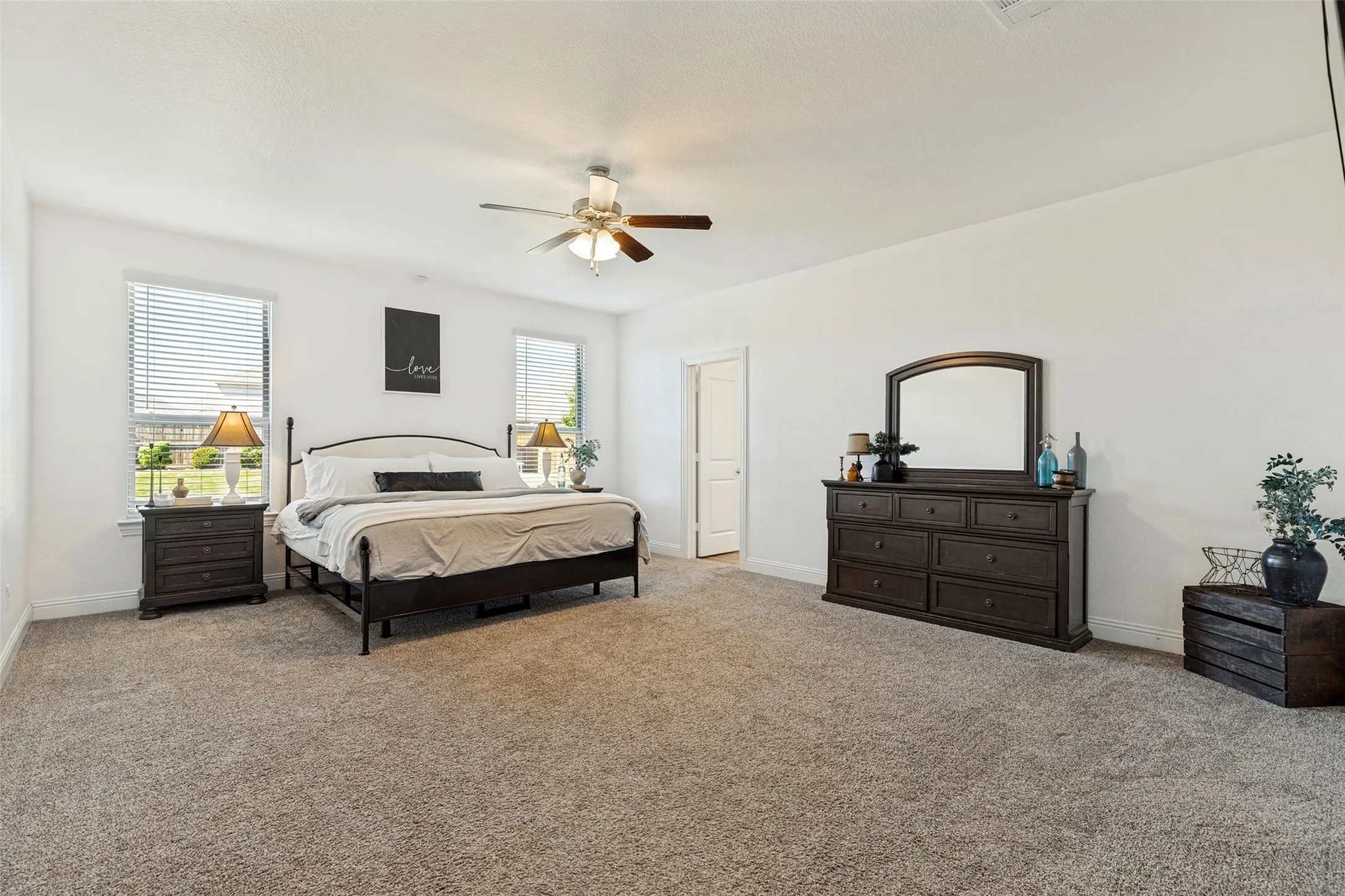 Spacious room featuring neutral carpeting, white walls, and multiple windows with blinds