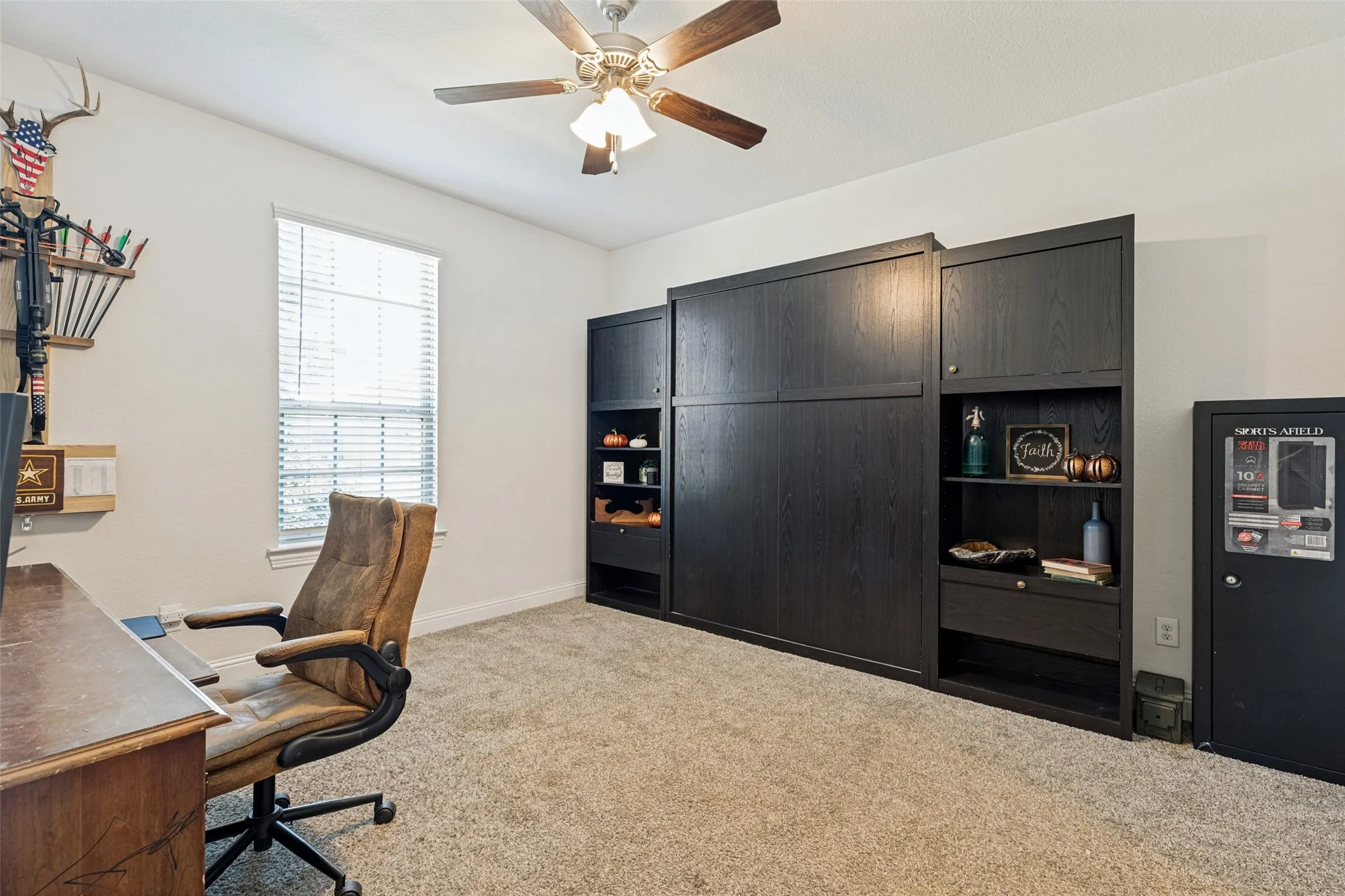 Murphy bed with cabinetry with integrated shelving, ceiling fan with light fixture, and window with blinds. En-suite bath