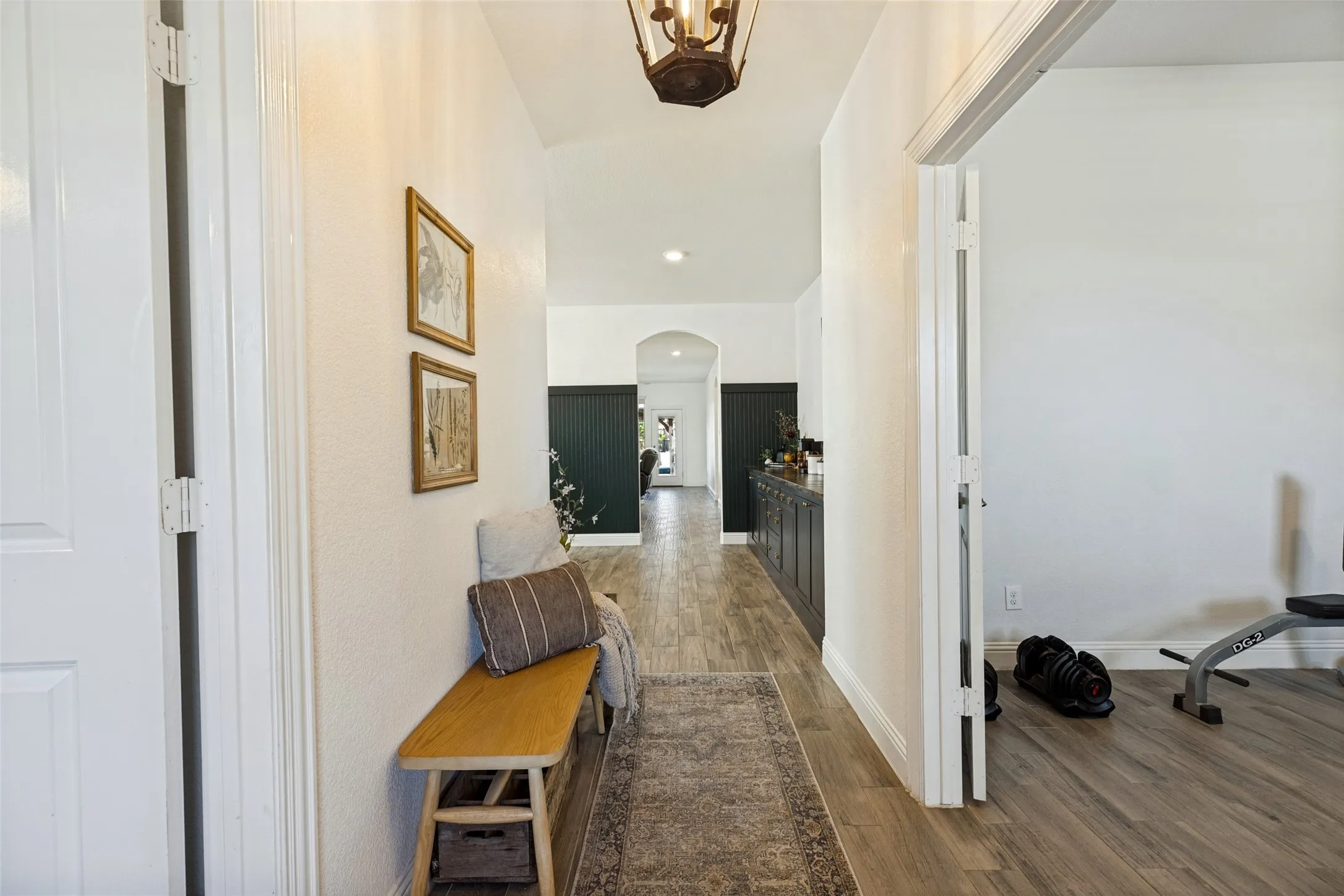 Hallway with wood-finish flooring, white walls, and a decorative overhead light fixture