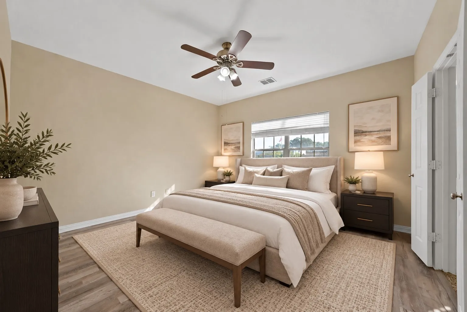 Upstairs primary bedroom with ensuite bathroom - virtually staged Ceiling fan, wide window with blinds, and wood-look flooring. Double doors on the right side of the room.
