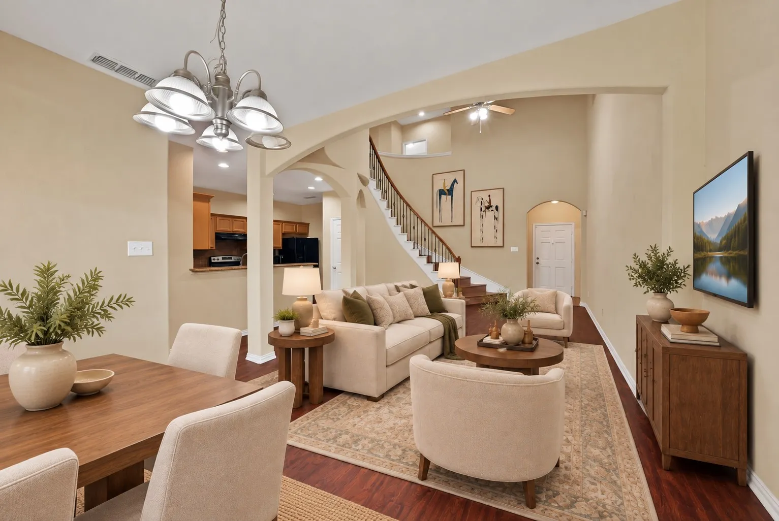 Dining and living area: Open layout with arched openings and wood-look flooring. View into the kitchen and toward the curved staircase. Virtually Staged