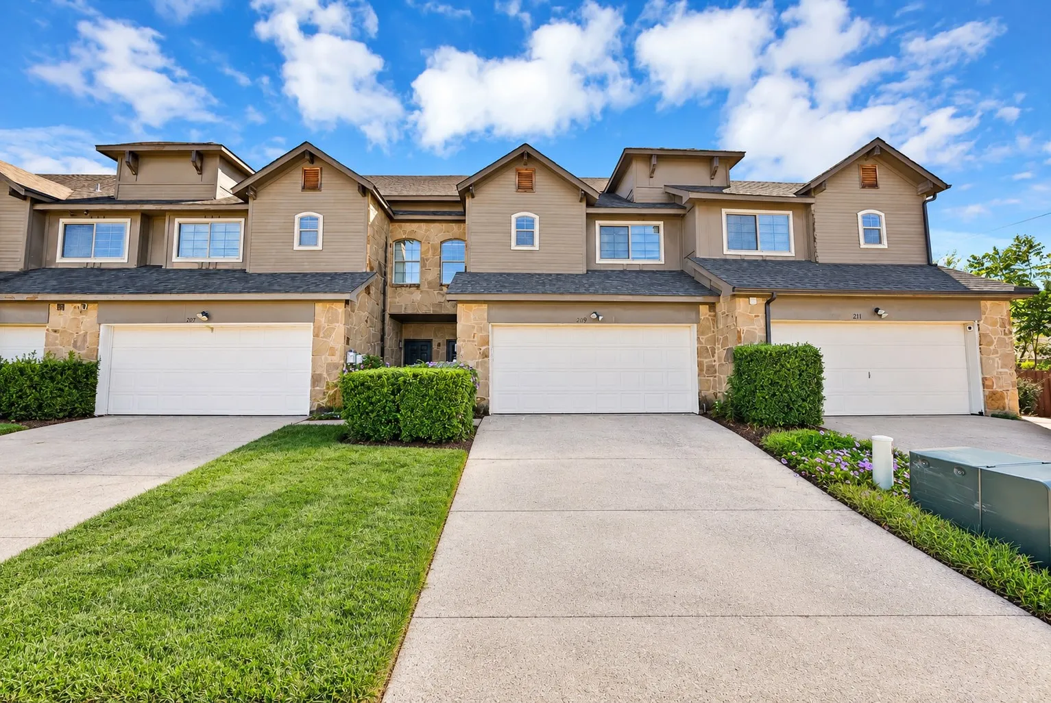 Front exterior: Stone accents, arched windows, and covered front entry. Two-car garage with wide driveway.