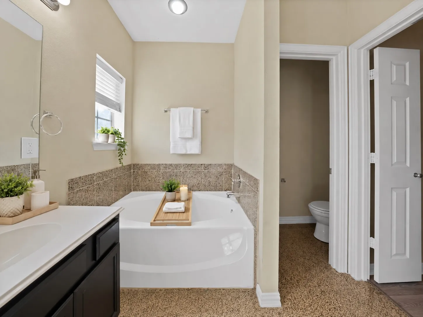 Upstairs primary ensuite bath: Garden tub with tile surround and window above. Private water closet with door.