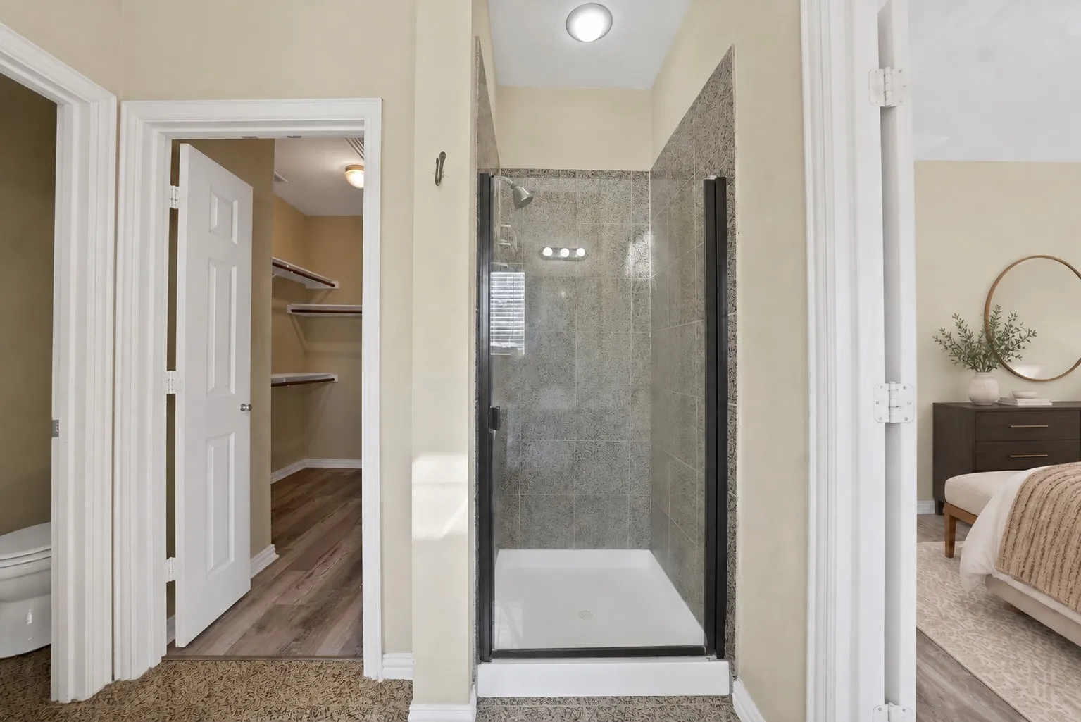 Upstairs primary ensuite bath: Walk-in shower with glass door and floor-to-ceiling tile surround. Private water closet and direct access to the walk-in closet.